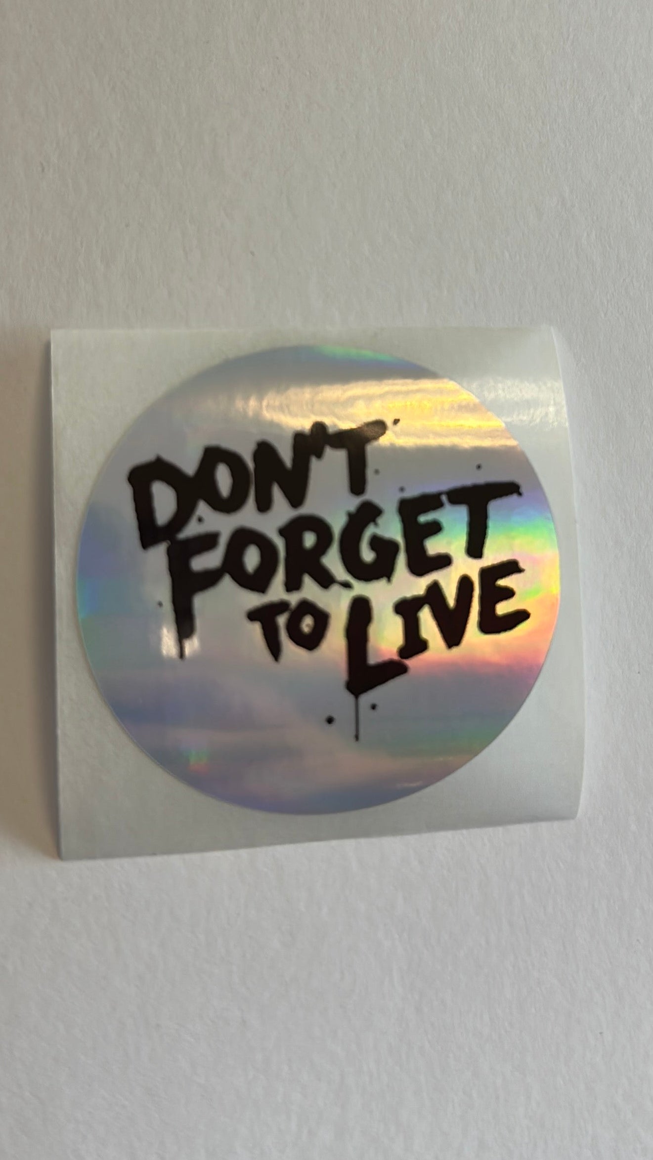 Sticker with 'Don't Forget to Live' text on a white surface