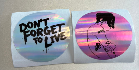 Two round stickers with motivational text and artistic design on a plain background