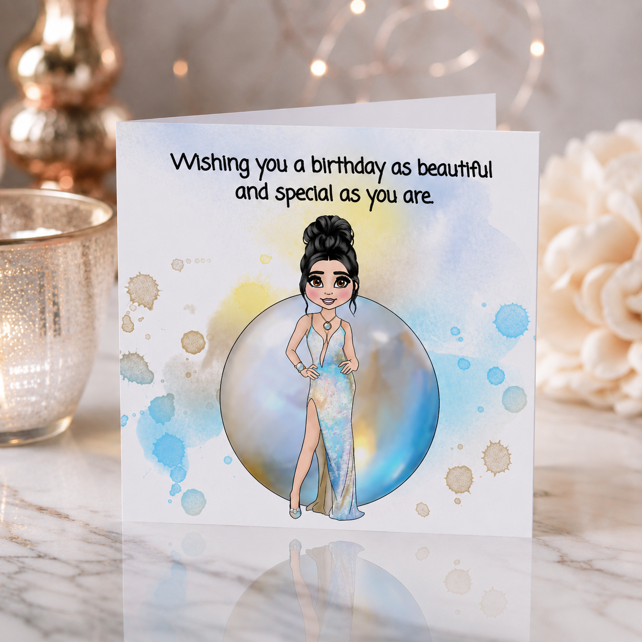 A square birthday greeting card with a cartoon illustration of a woman in a blue dress inside a bubble, placed on a marble surface with decorative candles and flowers in the background. The card reads, 'Wishing you a birthday as beautiful and special as you are.